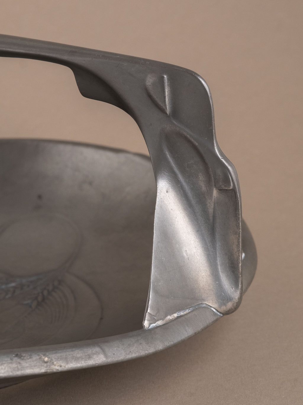 Side profile of Kayserzinn pewter handled bowl highlighting raised foot and geometric handle supports.
