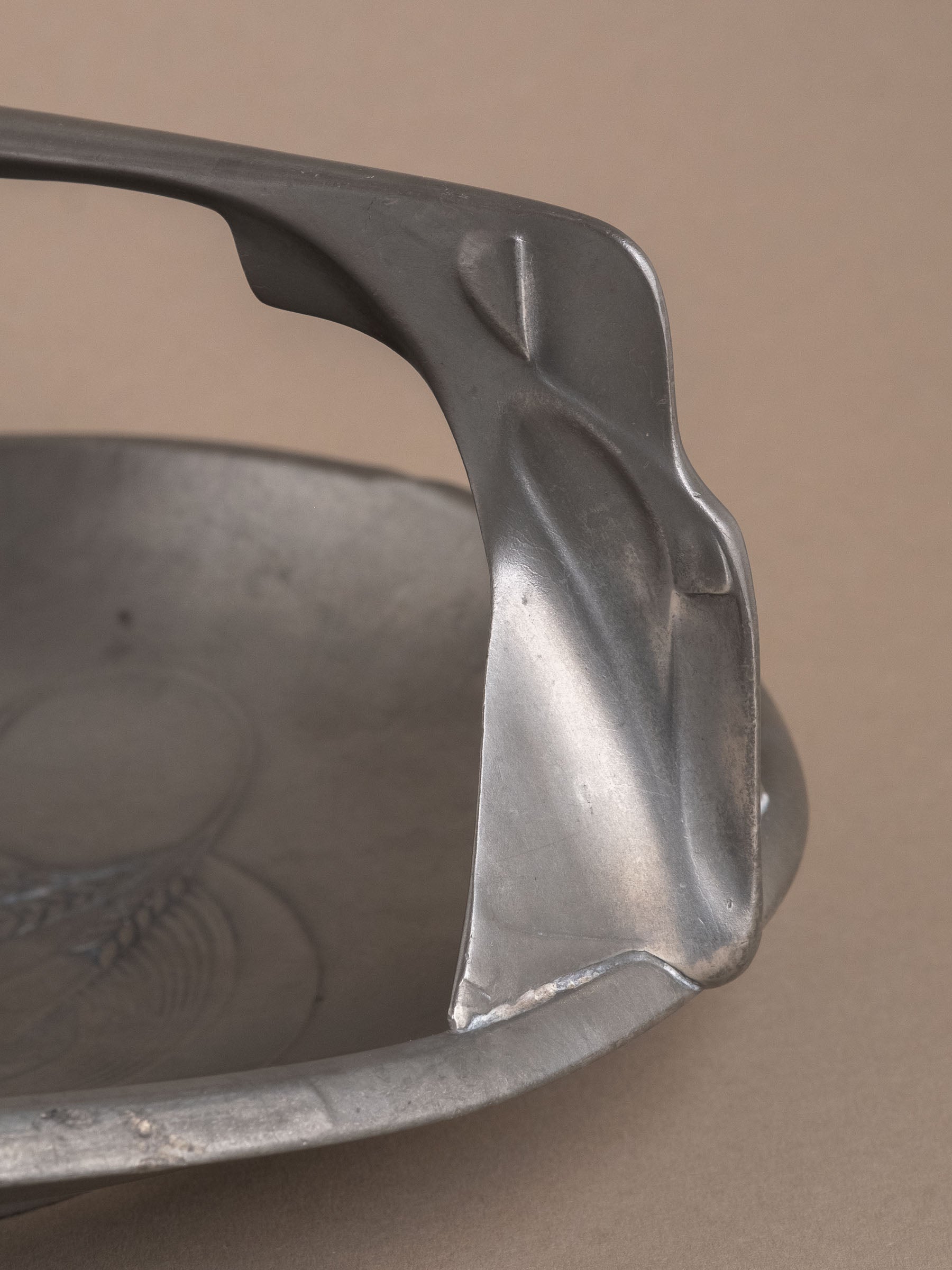 Side profile of Kayserzinn pewter handled bowl highlighting raised foot and geometric handle supports.
