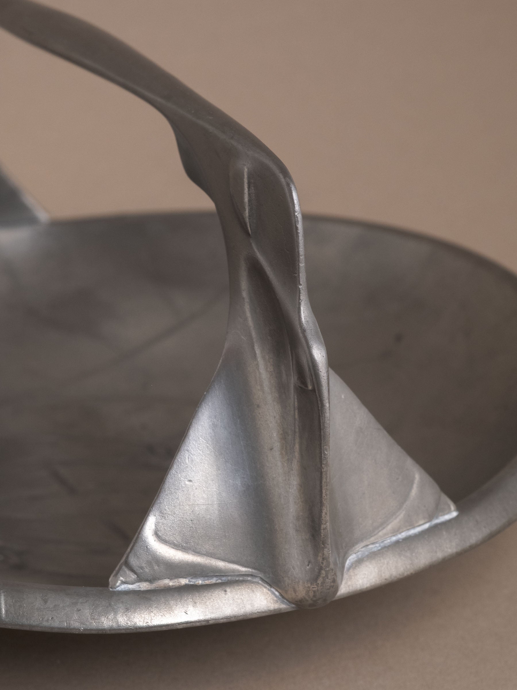 Close-up of one handle support on Kayserzinn pewter bowl showing cast form and surface wear.