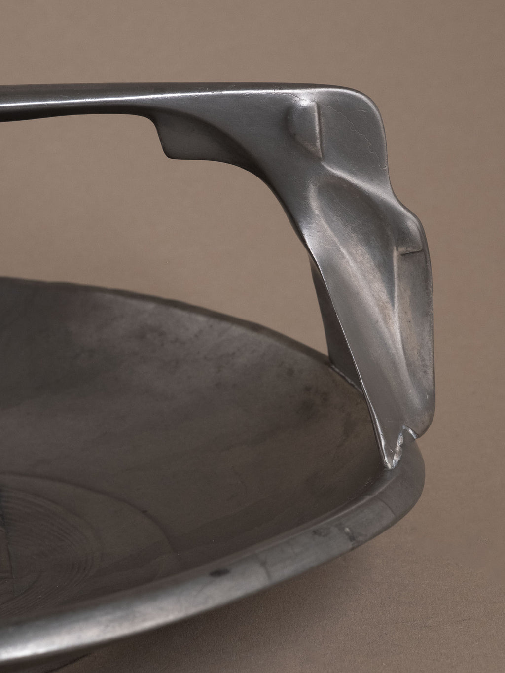 Close-up of sculptural pewter handle connection on Kayserzinn Art Nouveau bowl showing matte surface and angular support.
