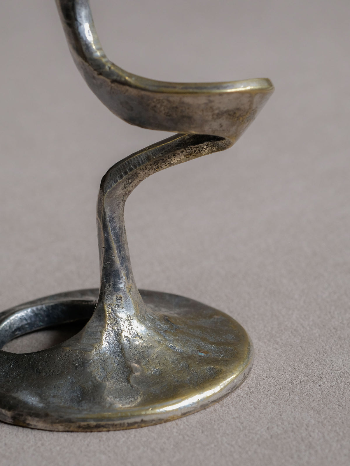 Detail of the silver-toned plated surface with warmer metal exposed through age-related rubbing and patina on the Kurt Jesch candleholder.