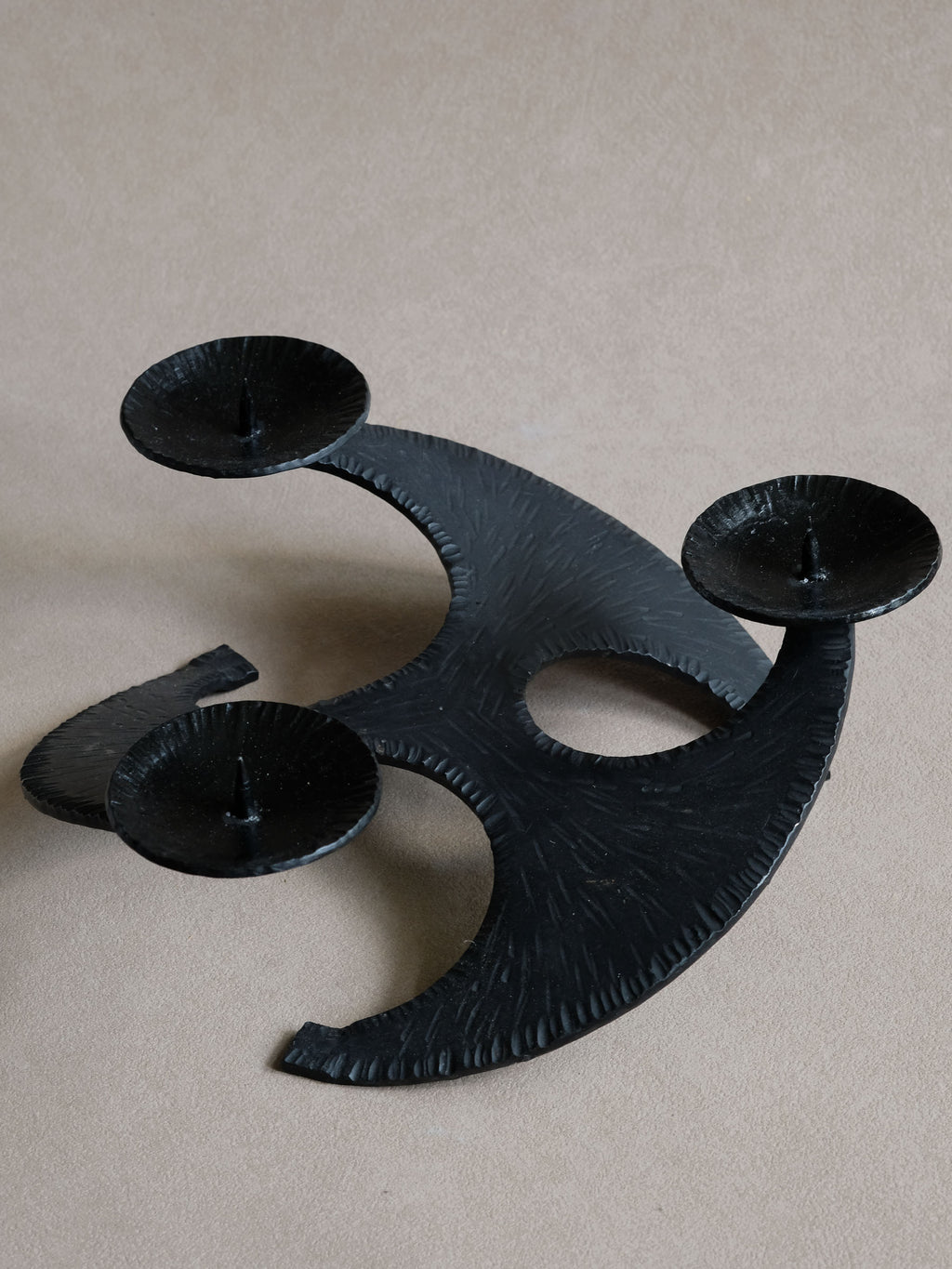 Top view of cast iron candleholder showing three pricket dishes and sweeping crescent-shaped arms.