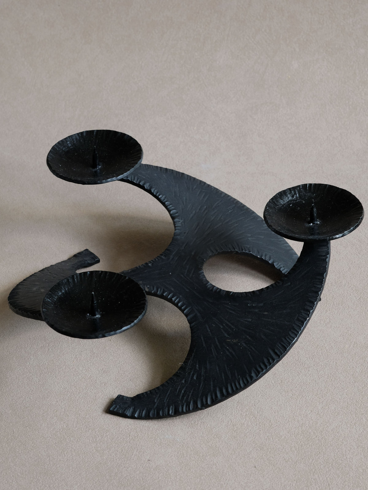 Top view of cast iron candleholder showing three pricket dishes and sweeping crescent-shaped arms.