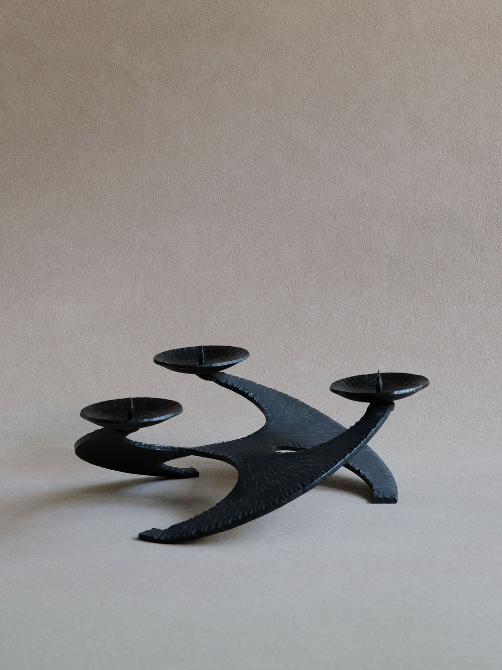 Side profile of large Brutalist cast iron candleholder showing its low sculptural stance.