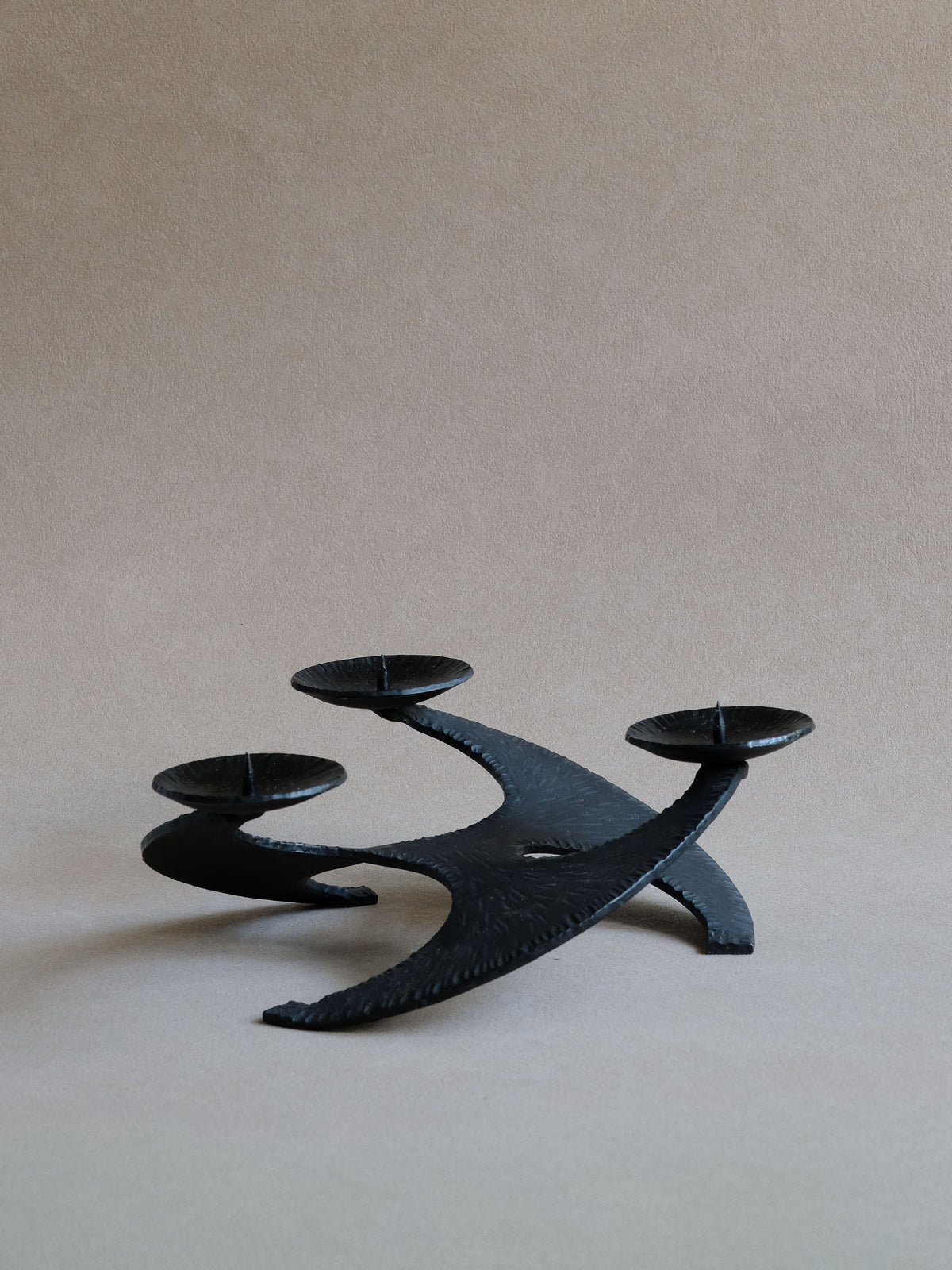 Side profile of large Brutalist cast iron candleholder showing its low sculptural stance.