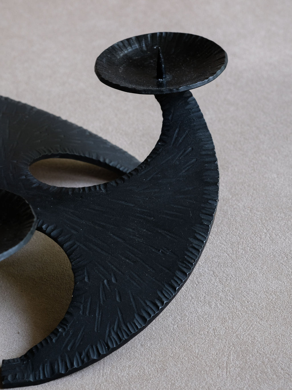 Close-up of rough striated cast iron surface and one pricket candle dish.