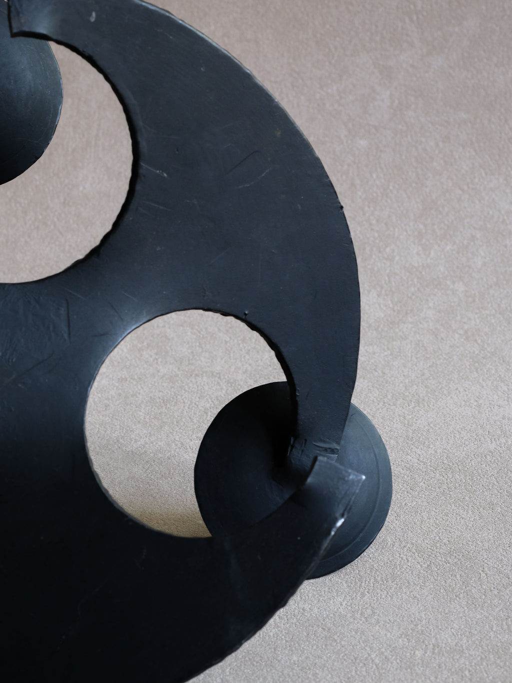Detail of circular negative space and textured cast iron body beneath a candle dish.