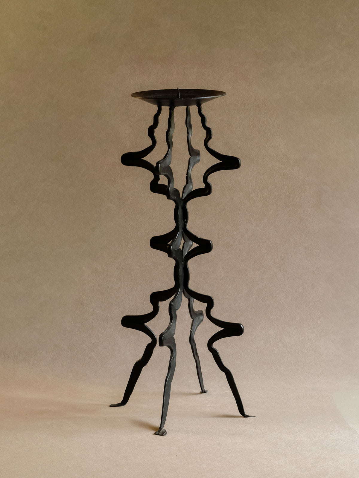 Angled view showing curved open iron construction of the large floor candleholder.