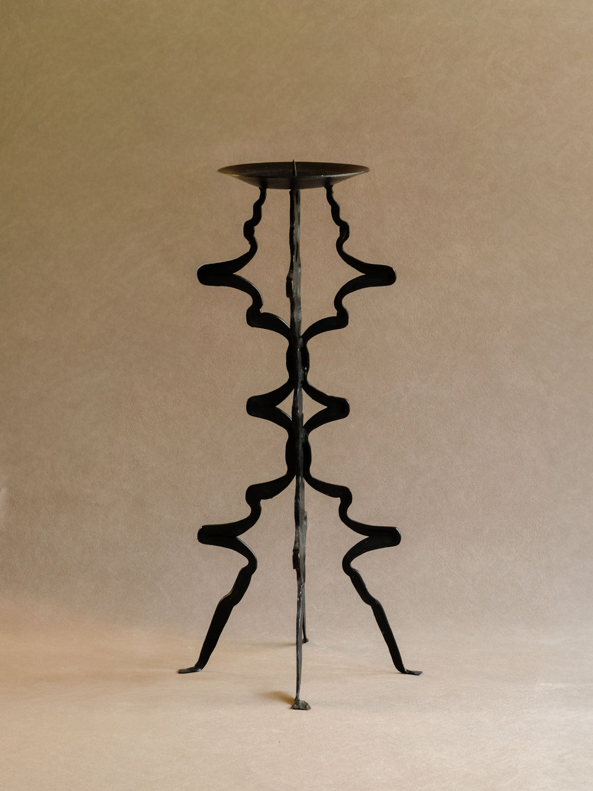Tall vintage blackened iron floor candleholder with broad circular top and branching stem.
