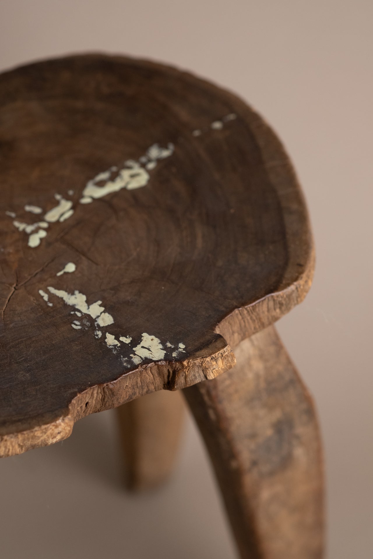 Detail of Lobi stool seat edge with natural crack, irregular carved rim, and aged wood texture.