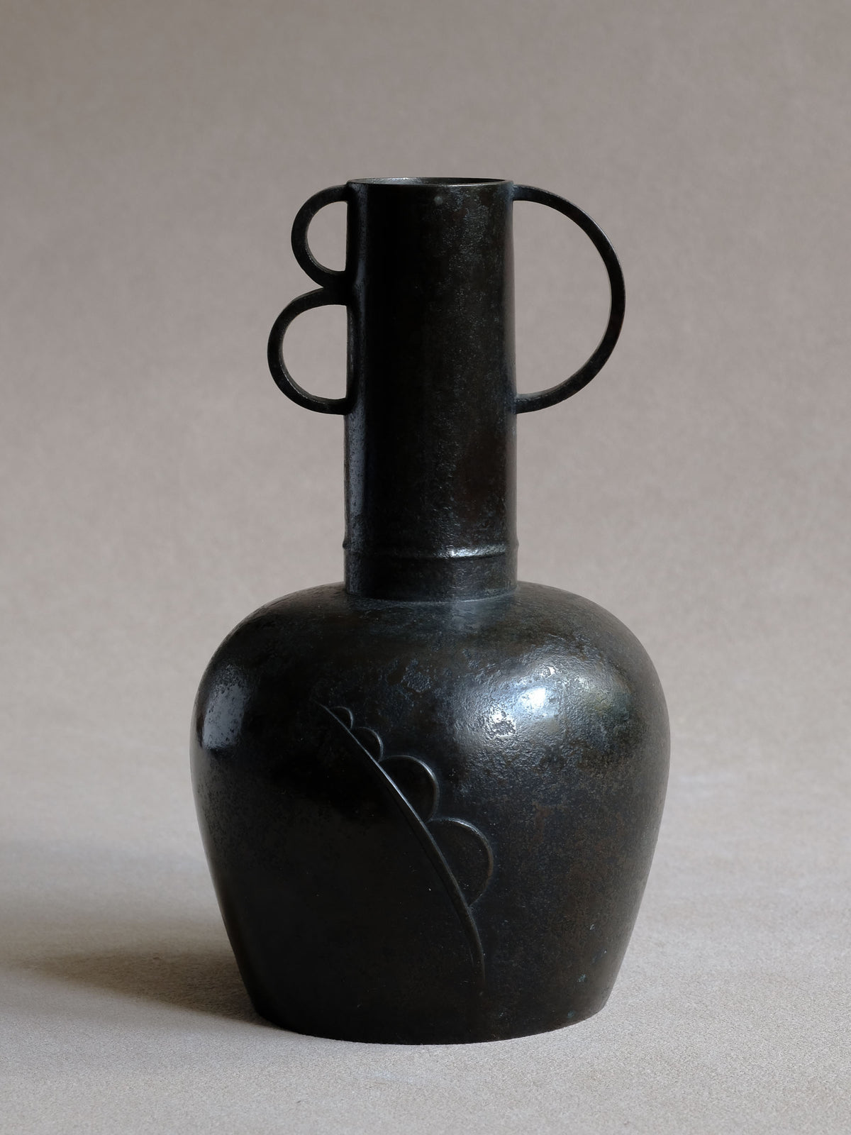 Maruyama Fubo modernist cast copper vase, front view with dark surface, geometric handles and raised body motif.