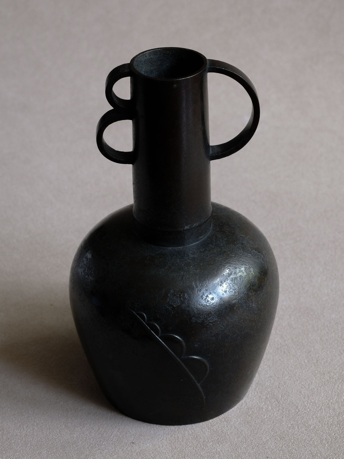 Three-quarter view of Maruyama Fubo copper vase with compact body, loop handles and raised decoration.