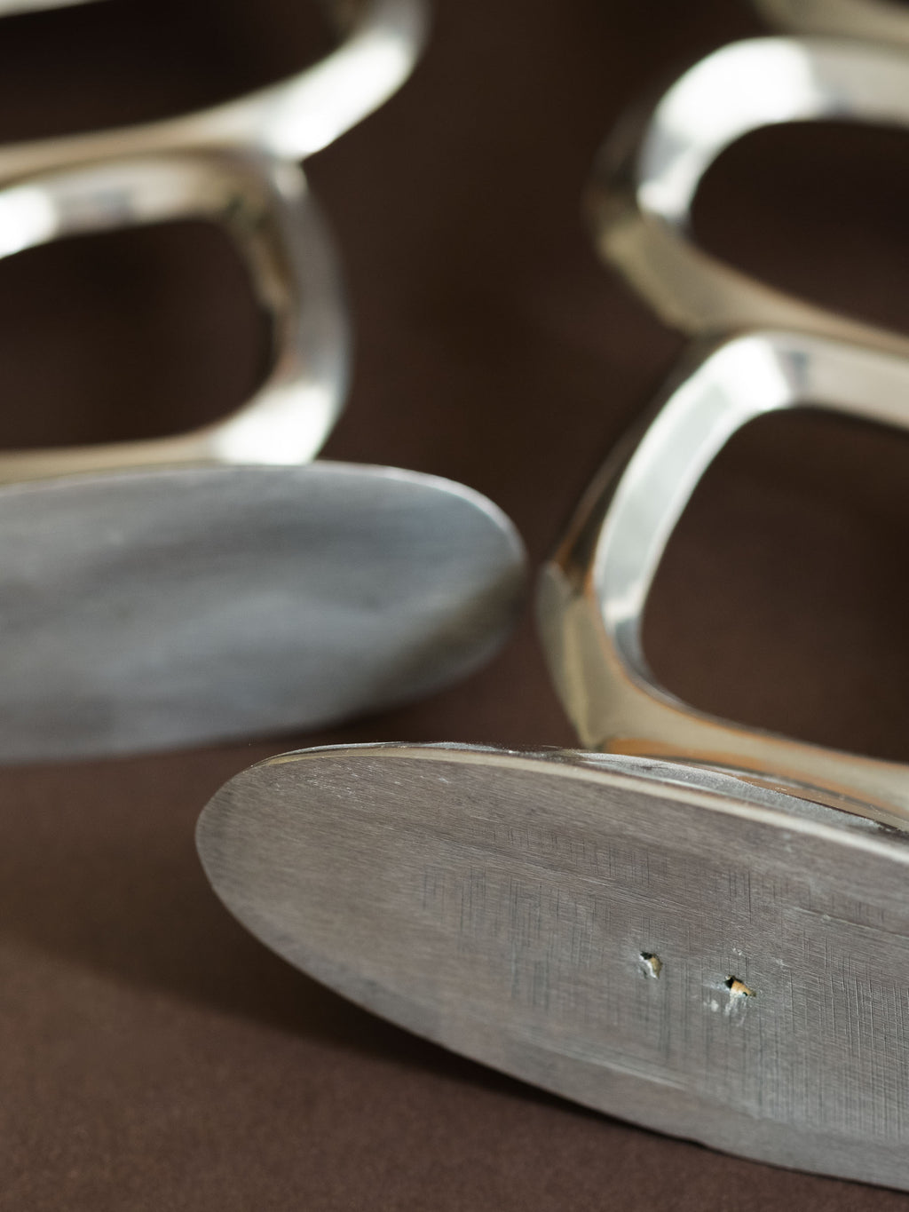 Close-up of the underside of a Matthew Hilton Circle candle holder, showing the brushed aluminium base and small surface marks.
