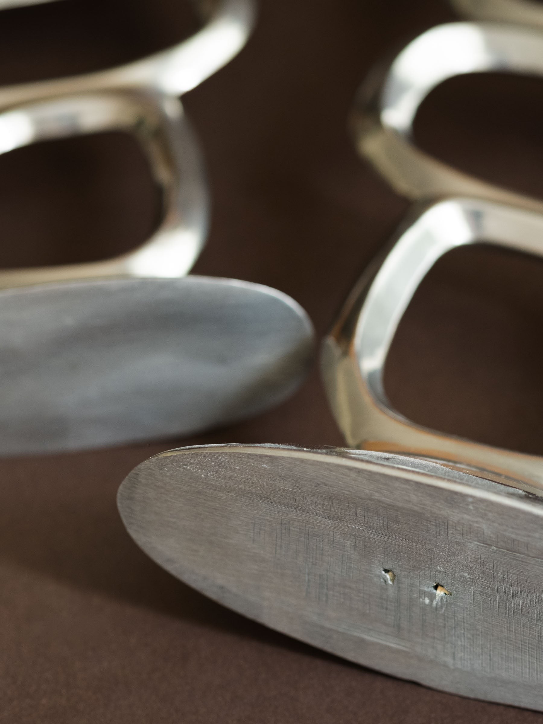 Close-up of the underside of a Matthew Hilton Circle candle holder, showing the brushed aluminium base and small surface marks.
