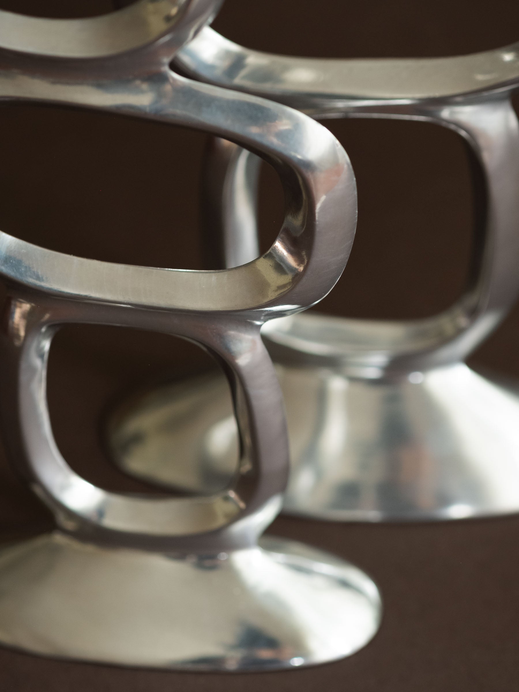 Close-up of the polished aluminium surface and rounded open ring form on the Matthew Hilton Circle candle holders.
