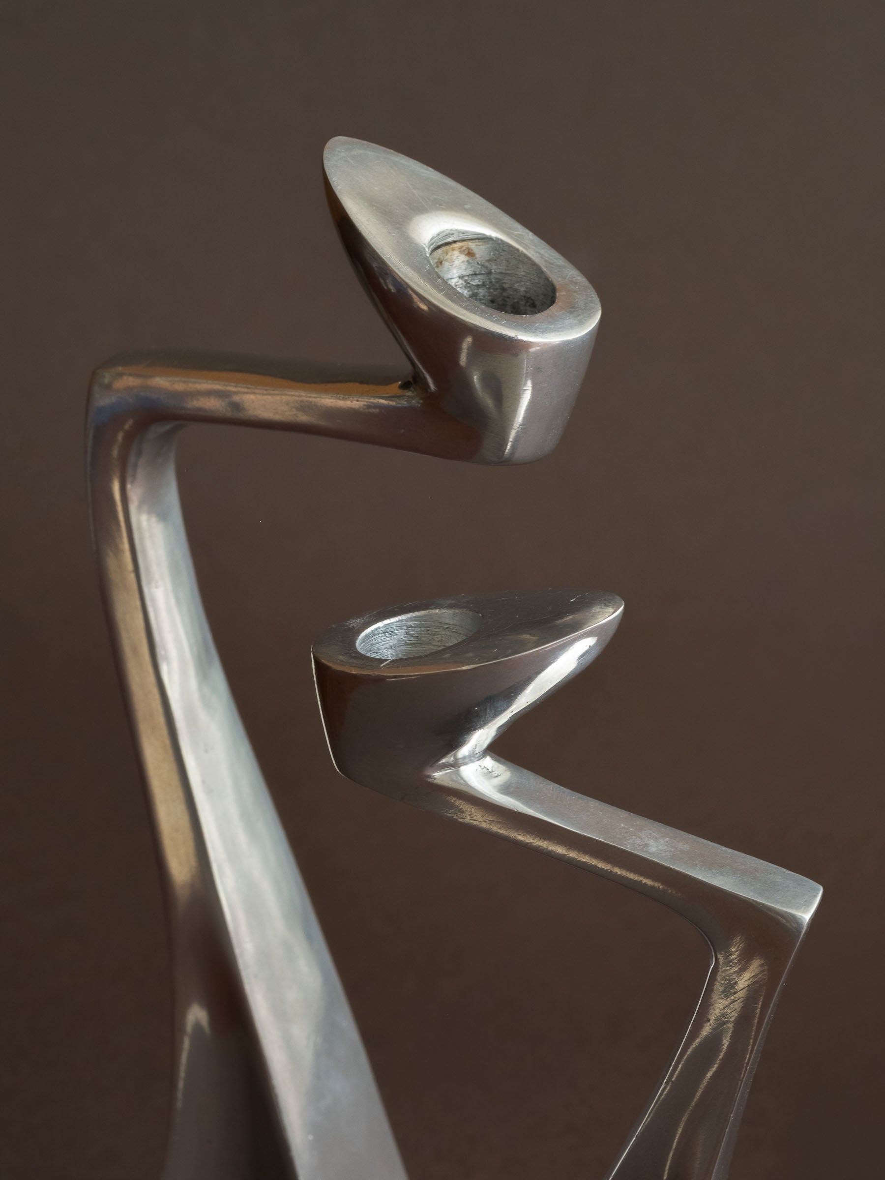 Close-up of the candle openings on the polished aluminium Swan candle holders, showing light surface wear inside the holders.
