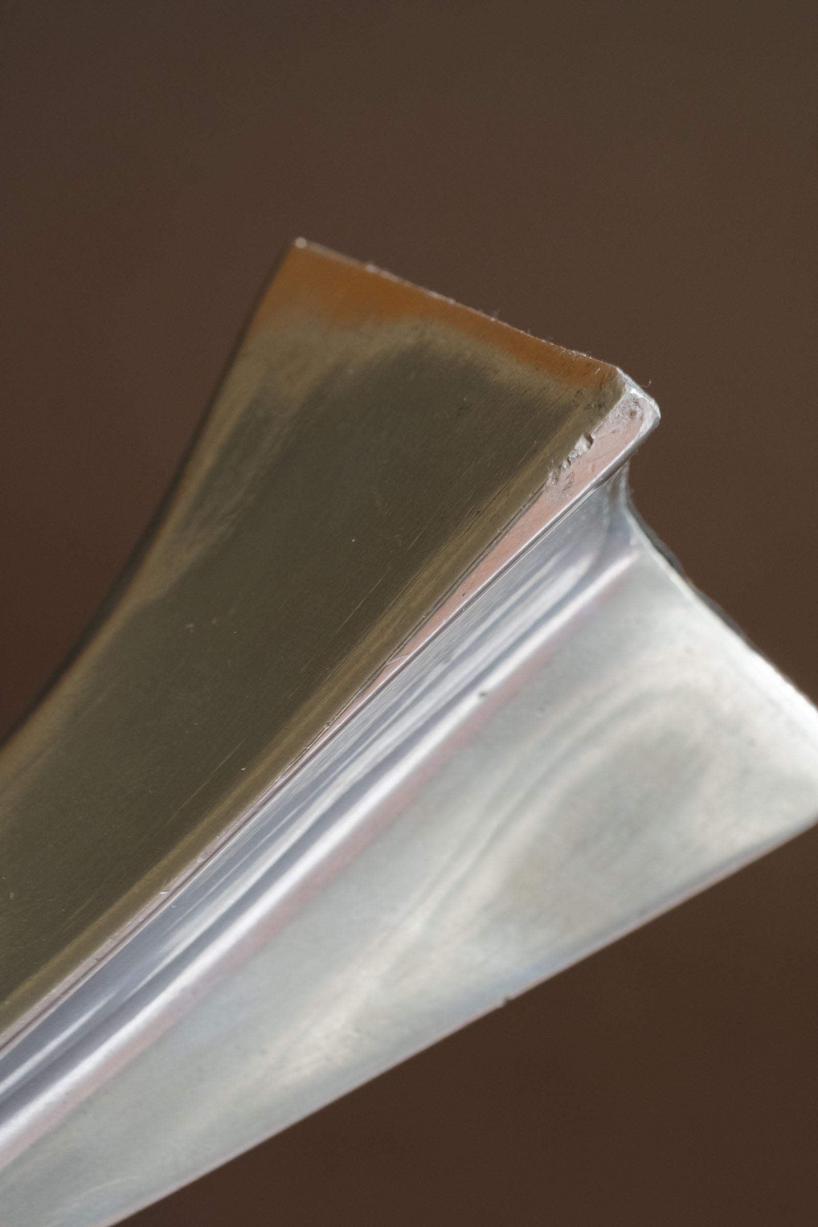 Close-up of the upper edge of a polished aluminium Swan candle holder, showing minor surface marks and age-related wear.
