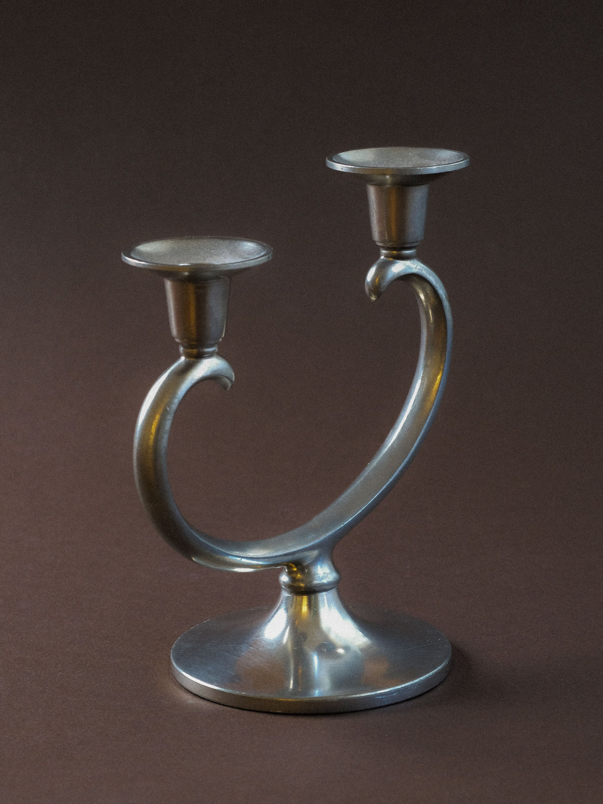 Alternate view of the vintage Metawa pewter candleholder showing the two curved arms and raised candle cups.