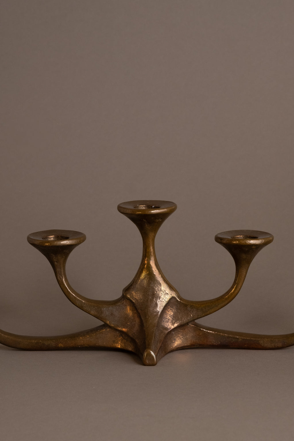 Close-up of central base of cast bronze candleholder showing sculptural form and patina.
