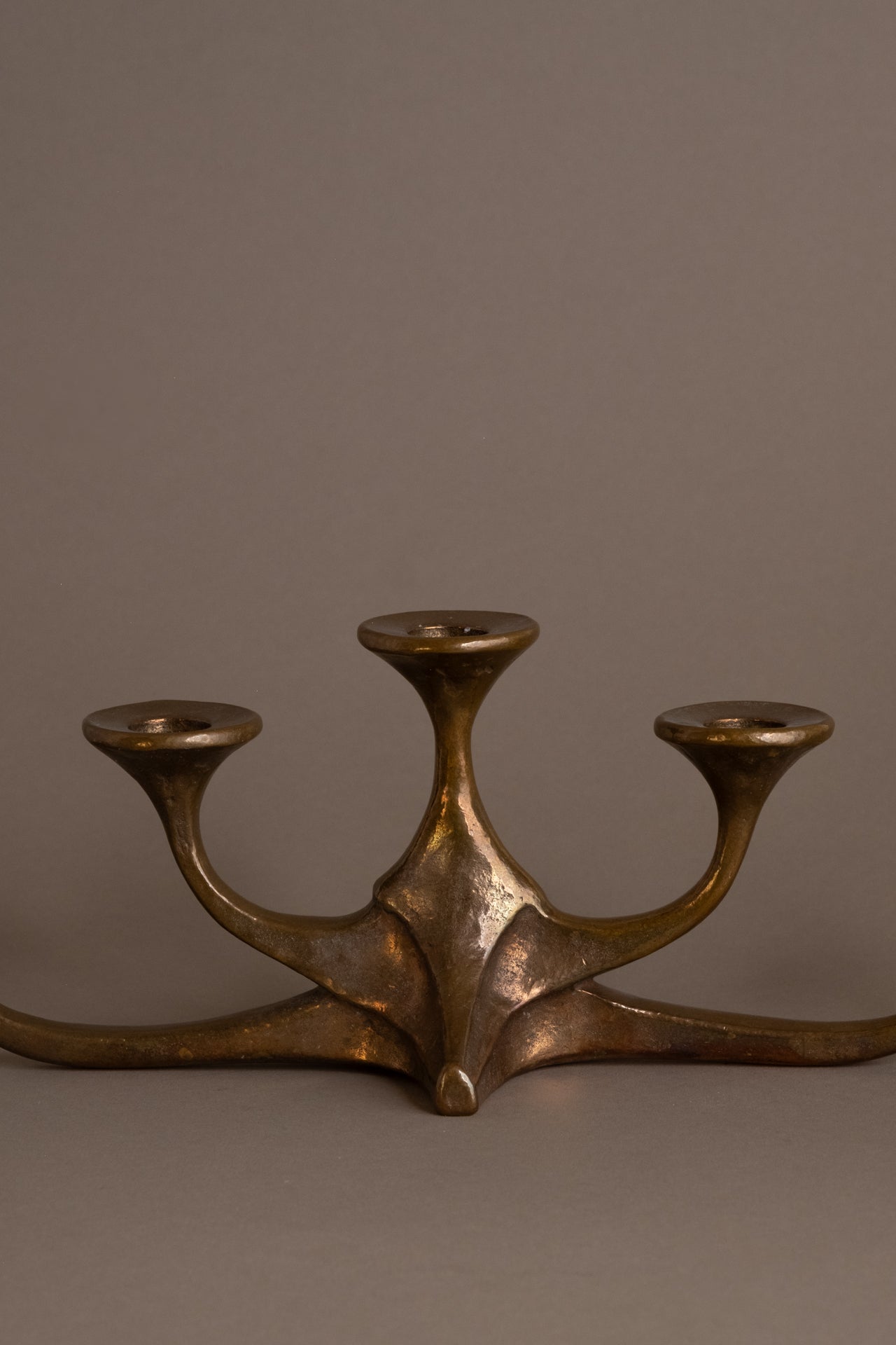 Close-up of central base of cast bronze candleholder showing sculptural form and patina.