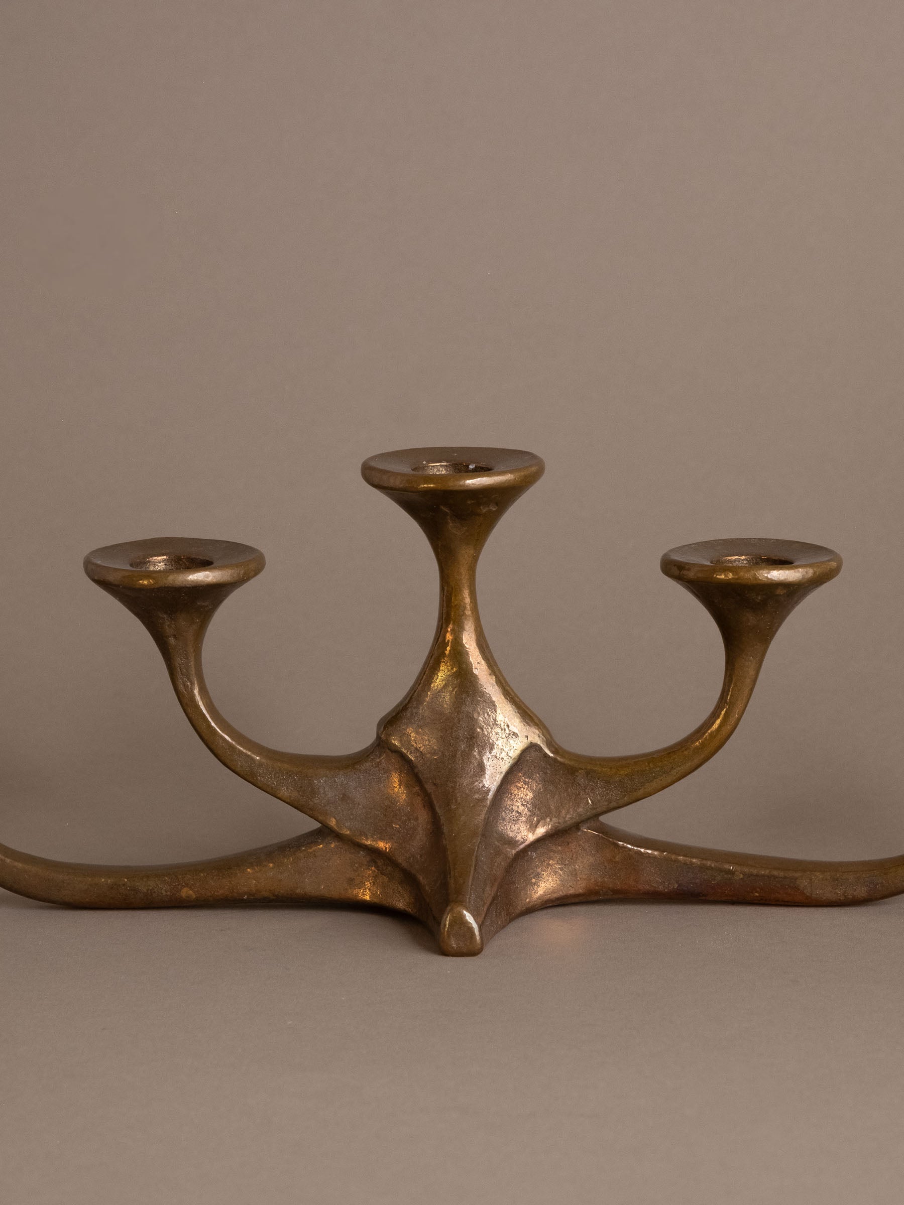 Close-up of central base of cast bronze candleholder showing sculptural form and patina.