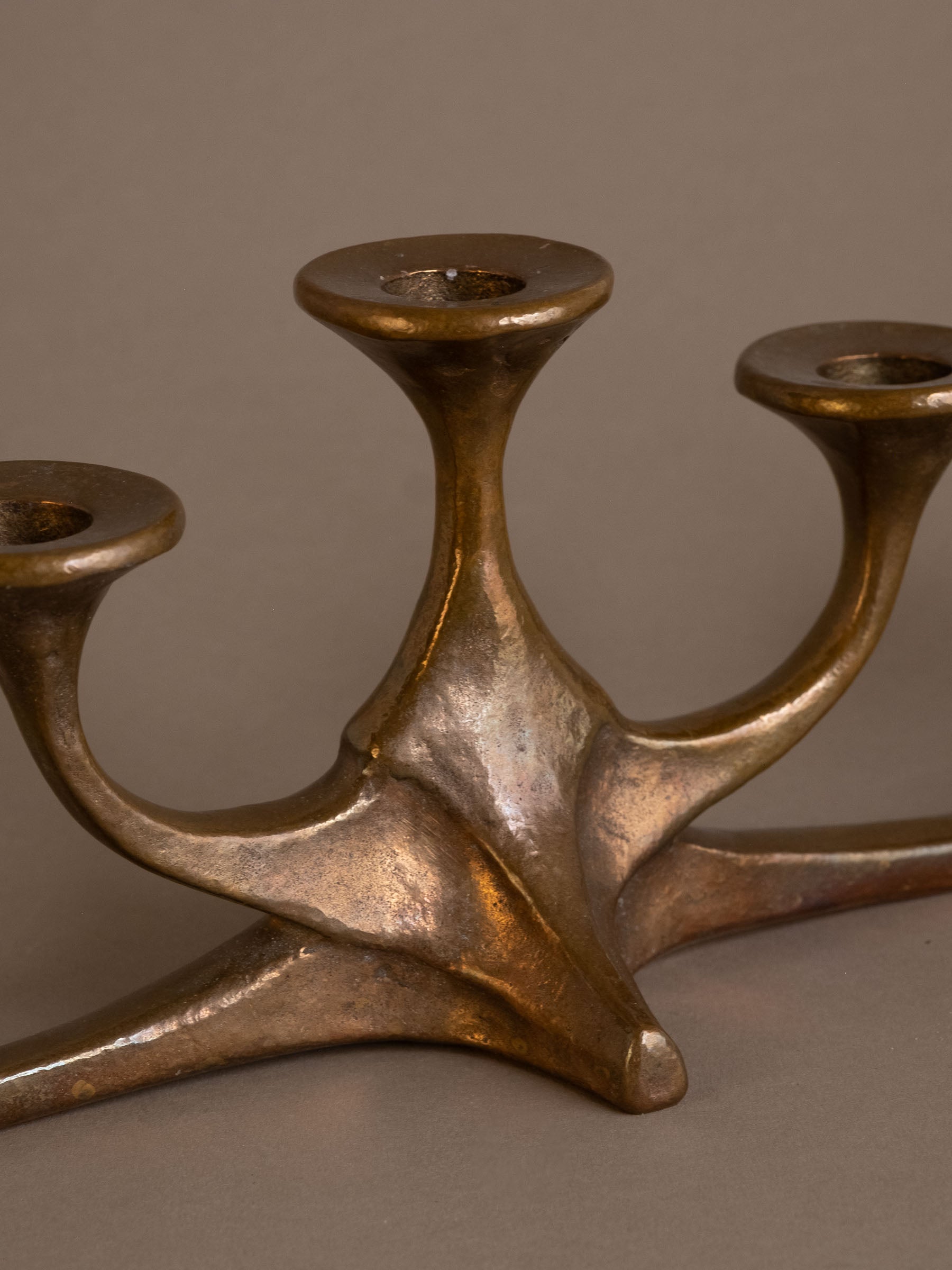 Close-up of central base of cast bronze candleholder showing sculptural form and patina.