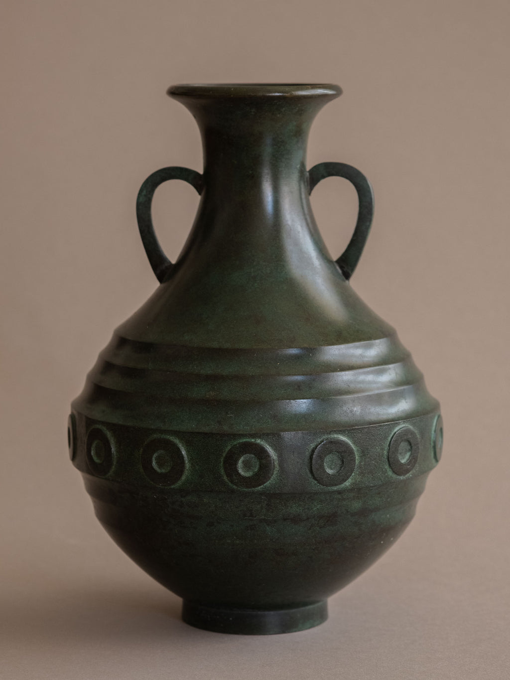 Front view of Japanese bronze vase with twin loop handles and flared neck against neutral background.