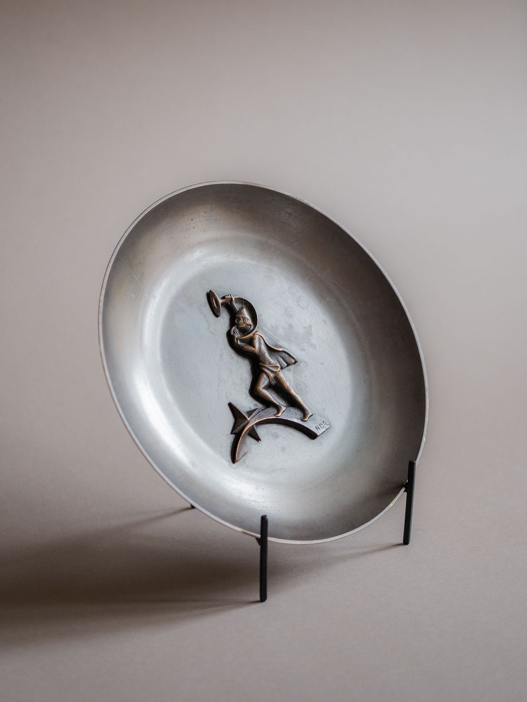Full angled view of the Nordisk Malm figural bronze dish on a black stand against a neutral background.