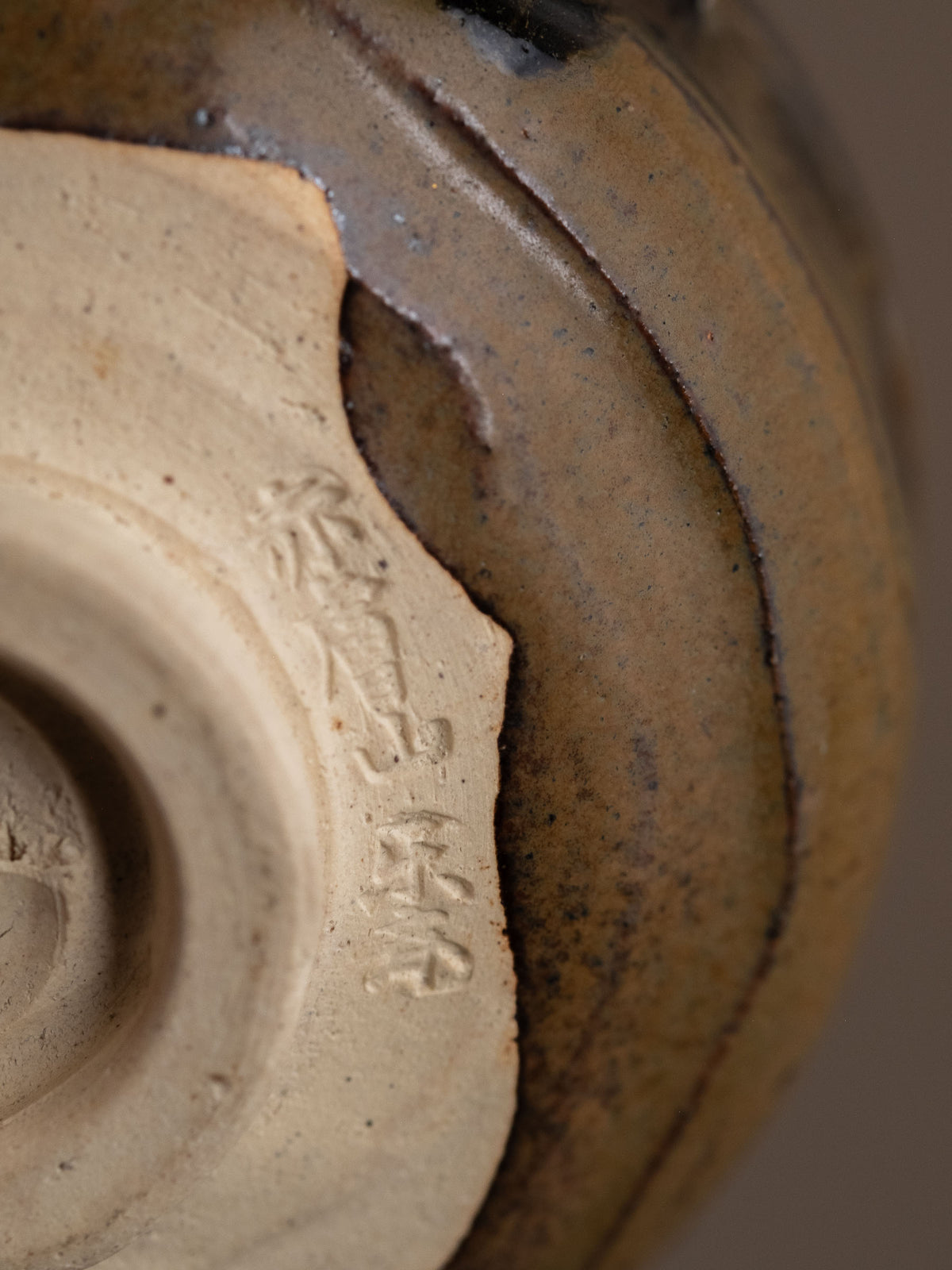 Underside of the Akahada ware (赤膚焼) tea bowl showing the unglazed foot and incised Rakusai (楽斎) mark.