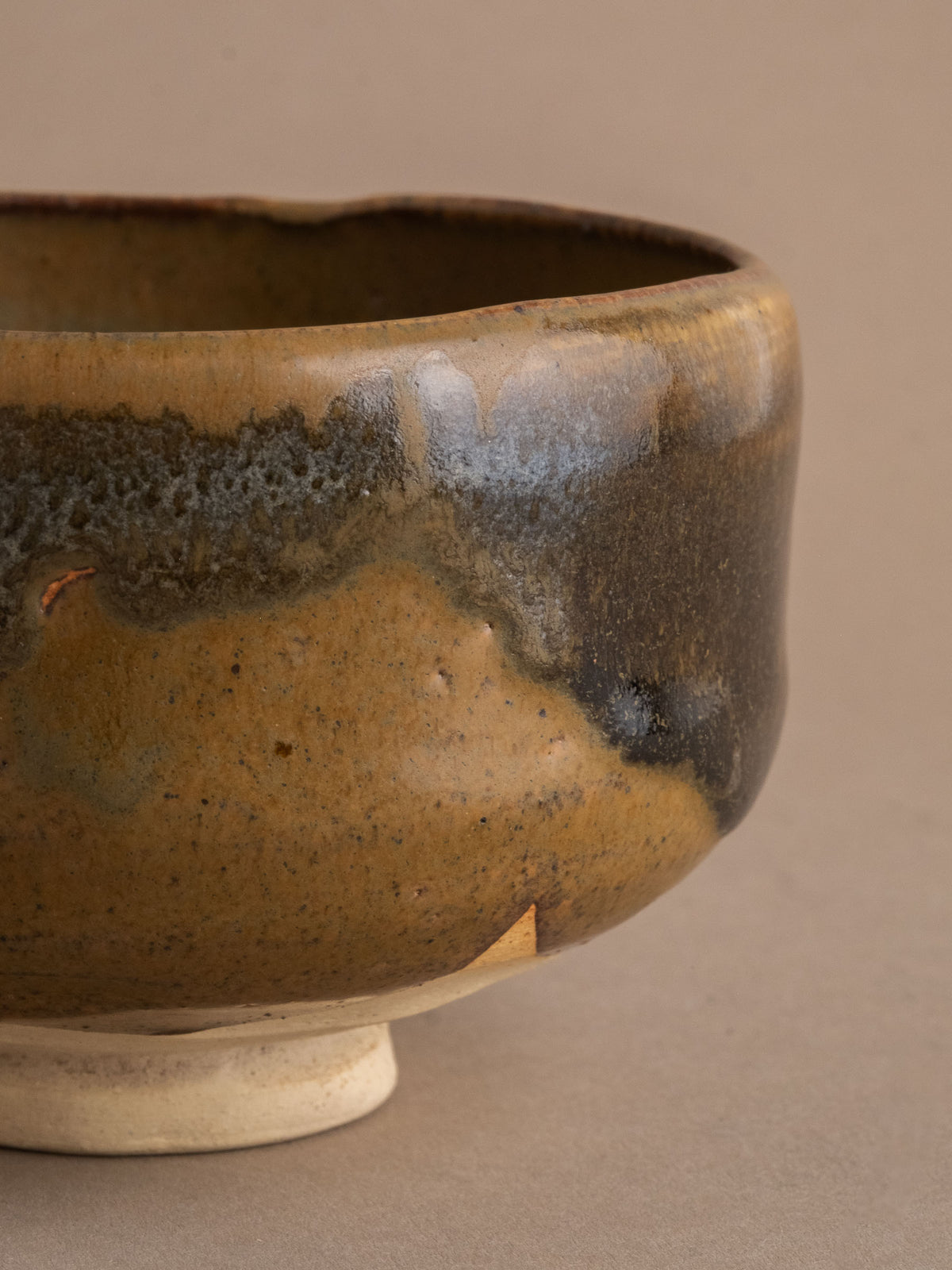 Close detail of the Akahada ware (赤膚焼) tea bowl showing amber, olive-grey and charcoal glaze transitions.