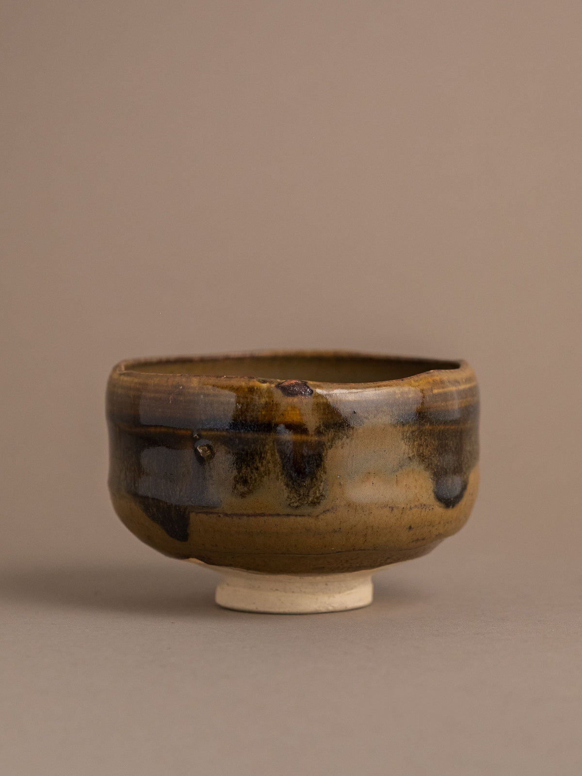 Onishi Rakusai Akahada ware (赤膚焼) tea bowl in front view, showing its warm amber-brown and charcoal flowing glaze.