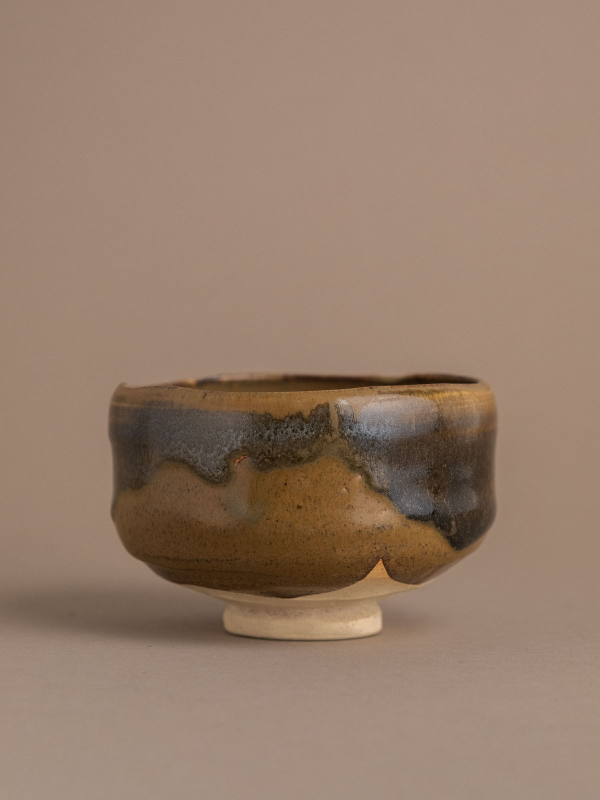 Alternate view of the Akahada ware (赤膚焼) tea bowl, showing its slightly asymmetric form and flowing dark glaze.