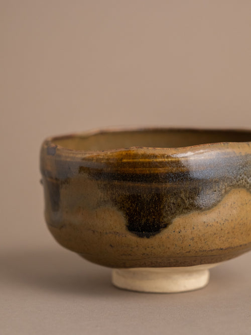 Side view of the Rakusai Akahada ware (赤膚焼) tea bowl with rounded body, raised foot and layered earthy glaze.