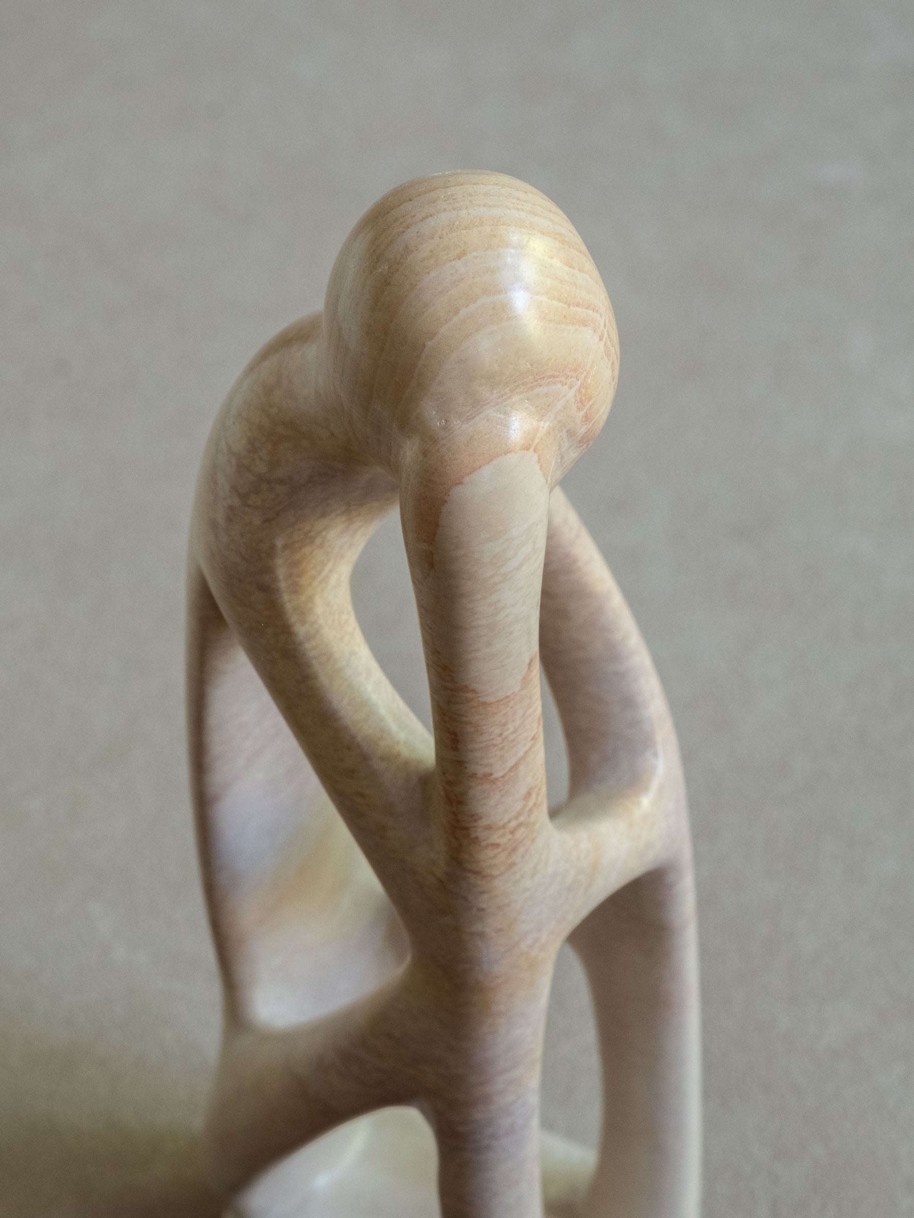 Three-quarter detail of the Kisii soapstone sculpture showing the intertwined upper form and open carved spaces.