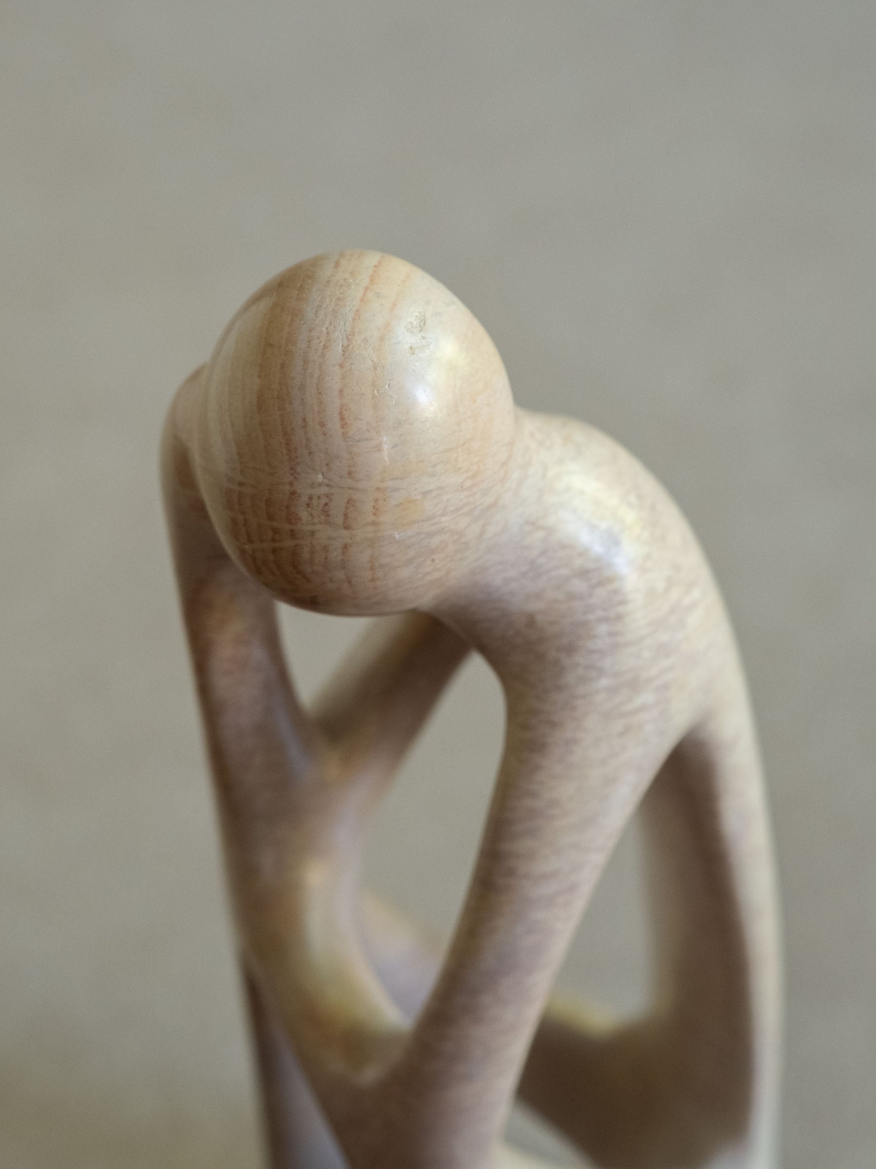 Close view of the rounded head and adjoining openwork on the pale Kenyan soapstone sculpture.