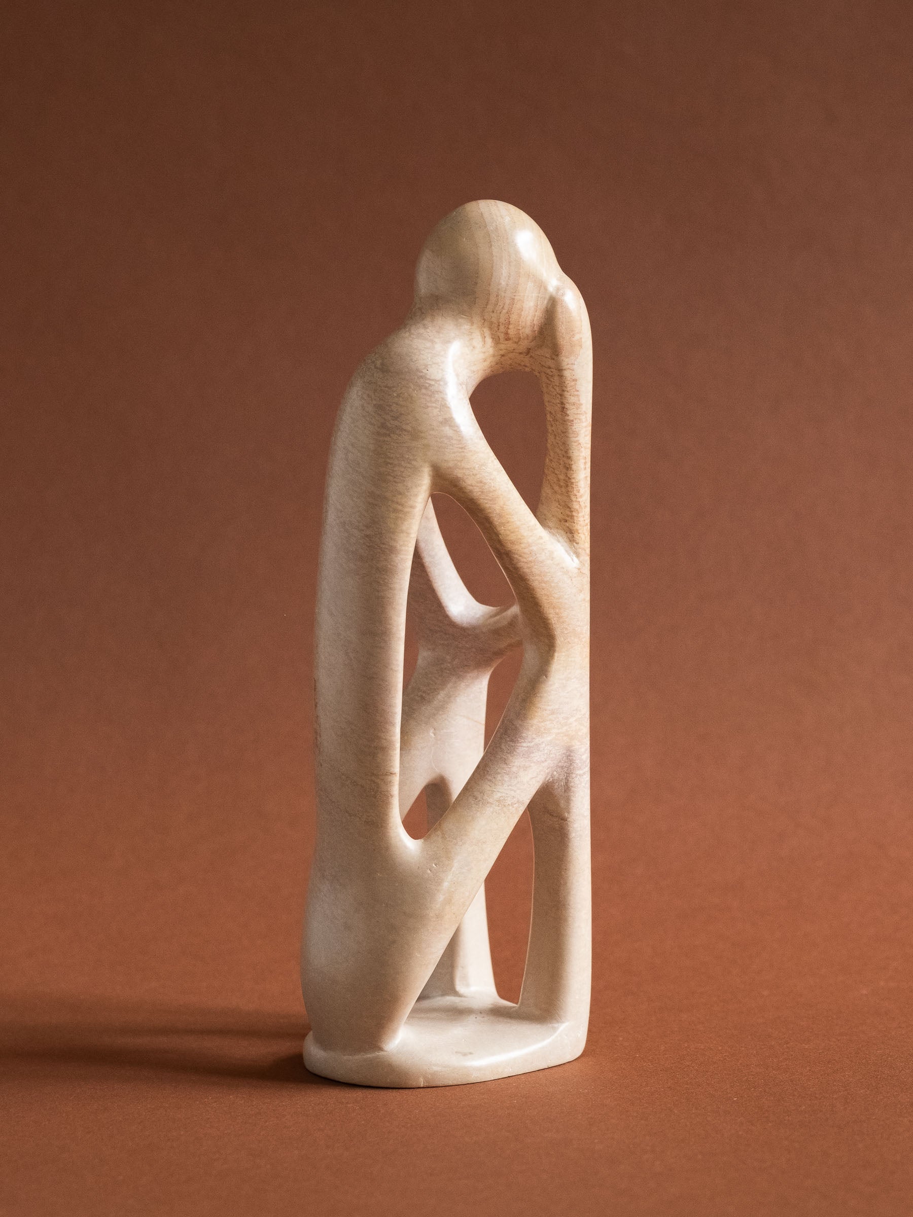 Full three-quarter view of the carved soapstone sculpture showing its elongated body and multiple negative spaces.