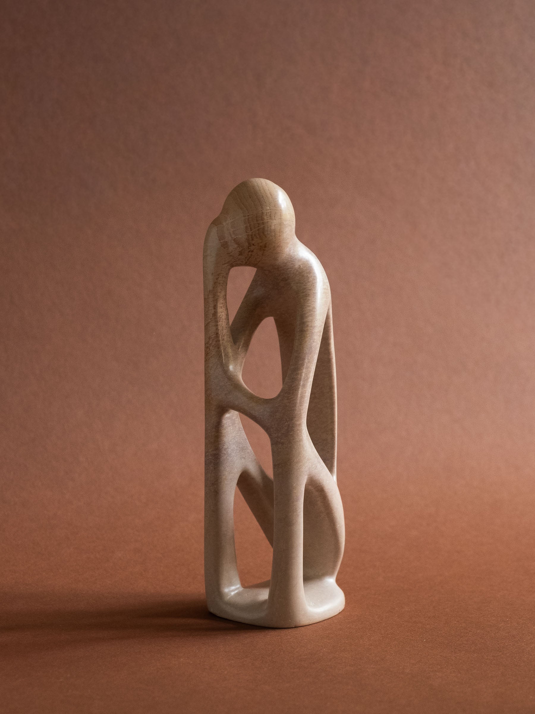Full front view of the pale Kisii soapstone sculpture with intertwined abstract human forms.
