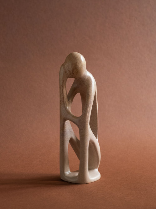 Full front view of the pale Kisii soapstone sculpture with intertwined abstract human forms.