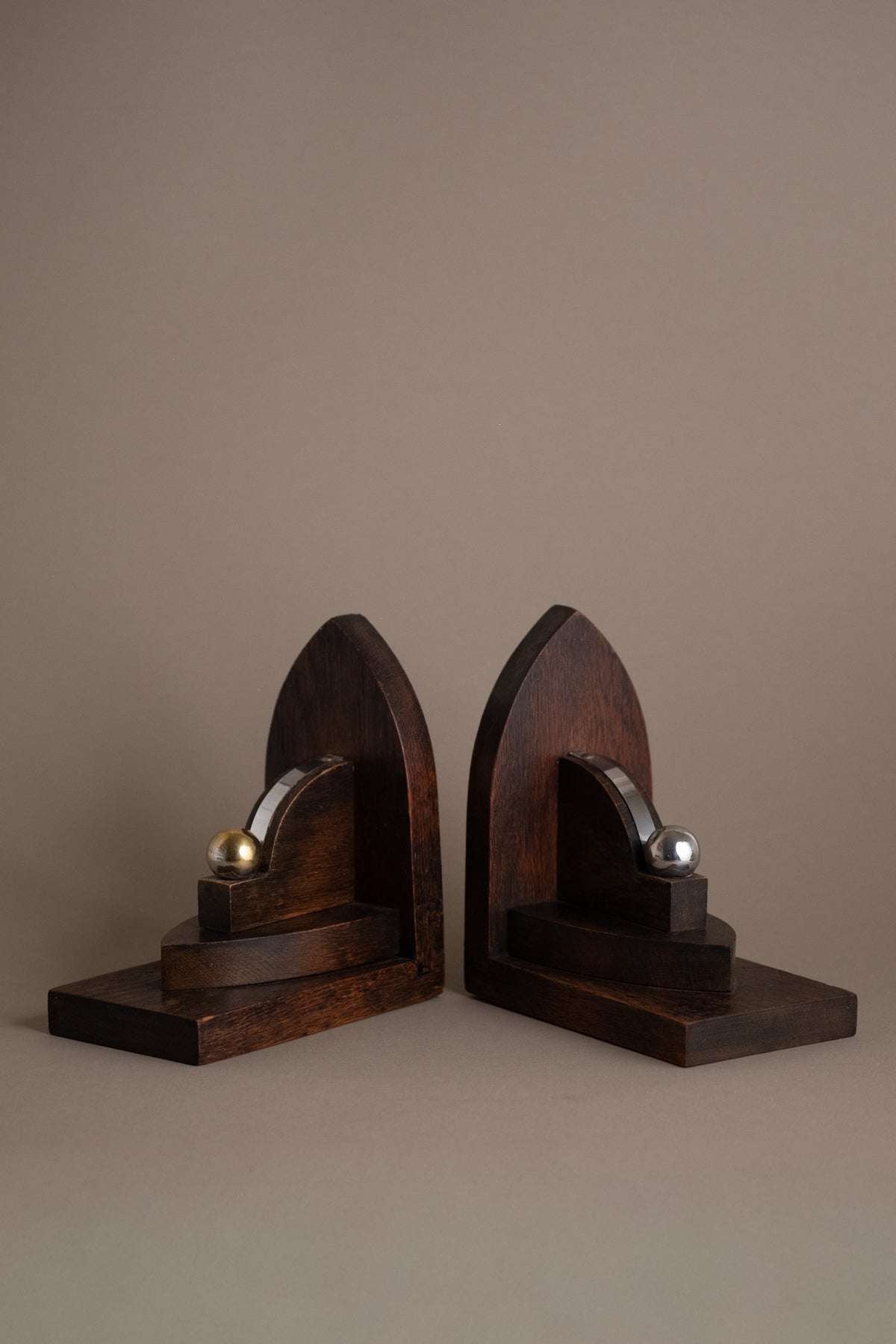 Pair of Amsterdam School oak bookends, Netherlands 1920s–30s, with geometric arched form and nickel-plated brass spheres.