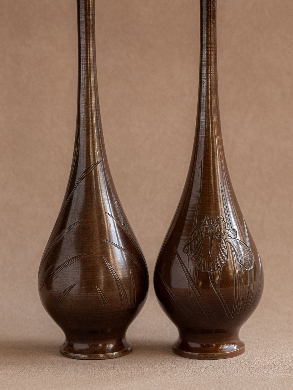 Full front view of a pair of tall Japanese metal bud vases with long necks and rounded bodies.