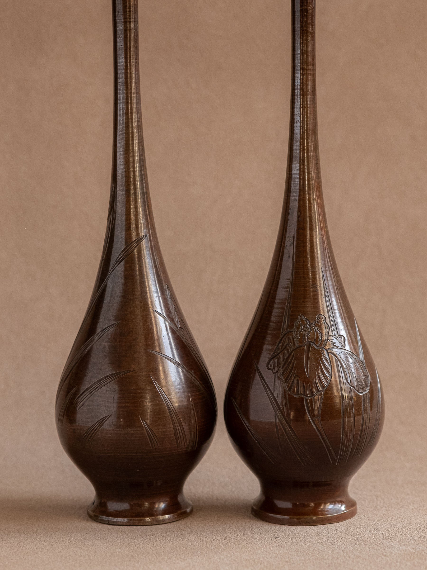 Full front view of a pair of tall Japanese metal bud vases with long necks and rounded bodies.