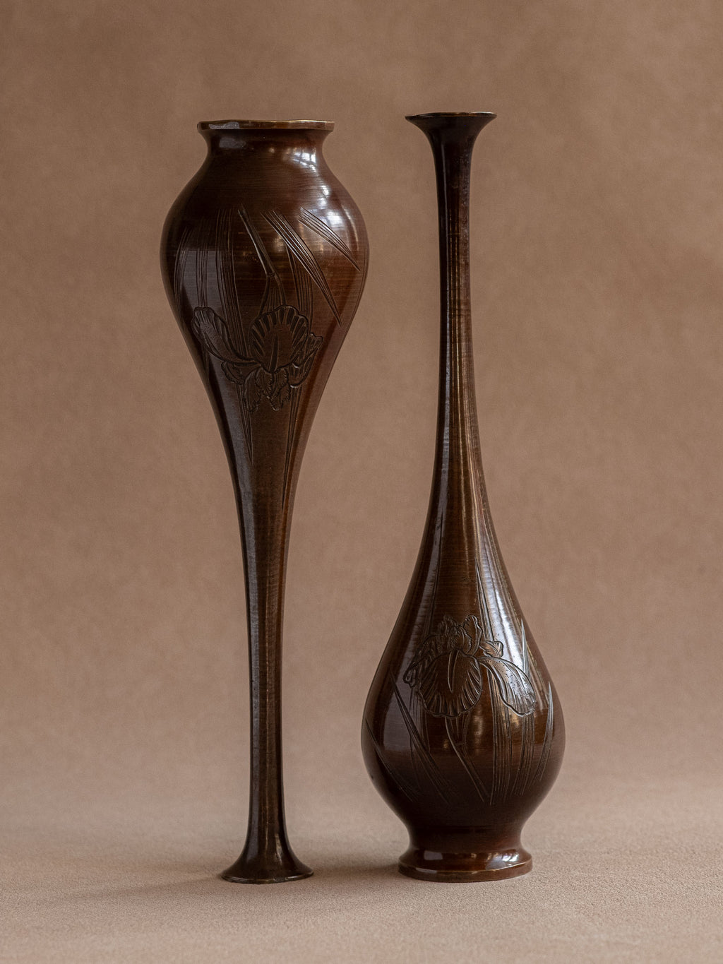 Japanese metal bud vase beside a tall slender comparison vase, showing the rounded body and long neck in profile.