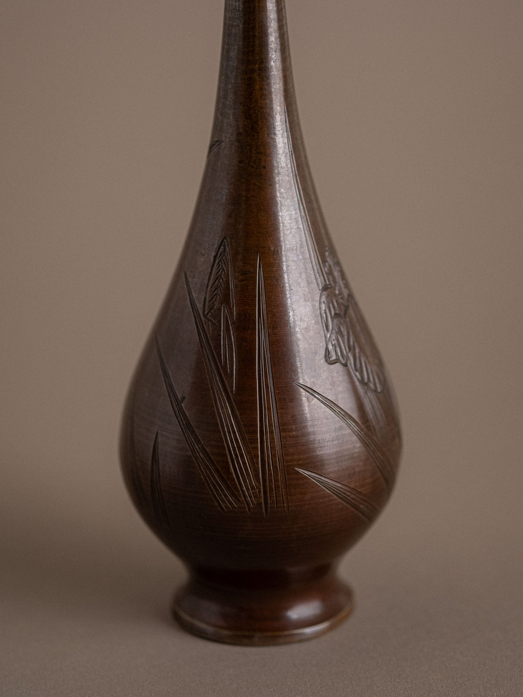 Single Japanese metal bud vase with brown patina, shown in side view with engraved leaf and iris details.