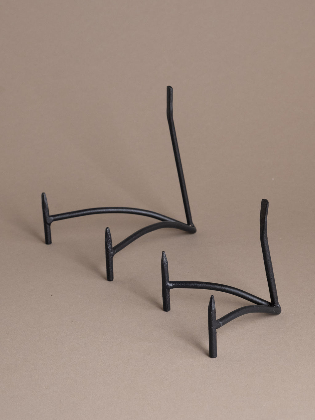 Two black iron plate display stands shown together against a taupe background, available in multiple sizes for plate and bowl display
