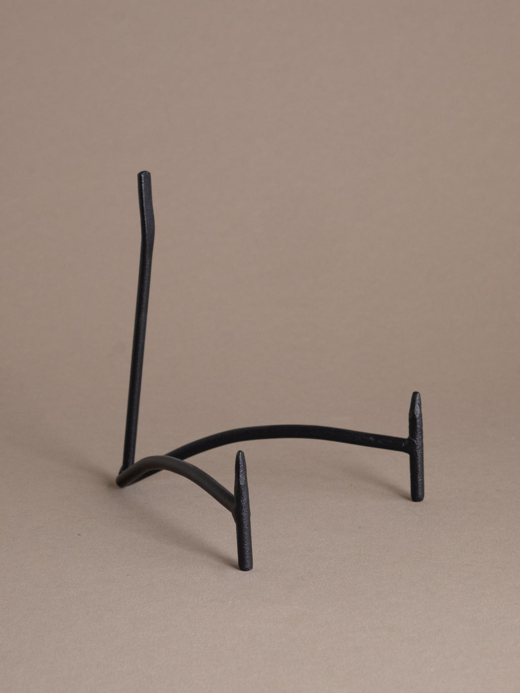 Black iron plate display stand shown empty against a taupe background, designed for displaying plates, shallow bowls, and small objects