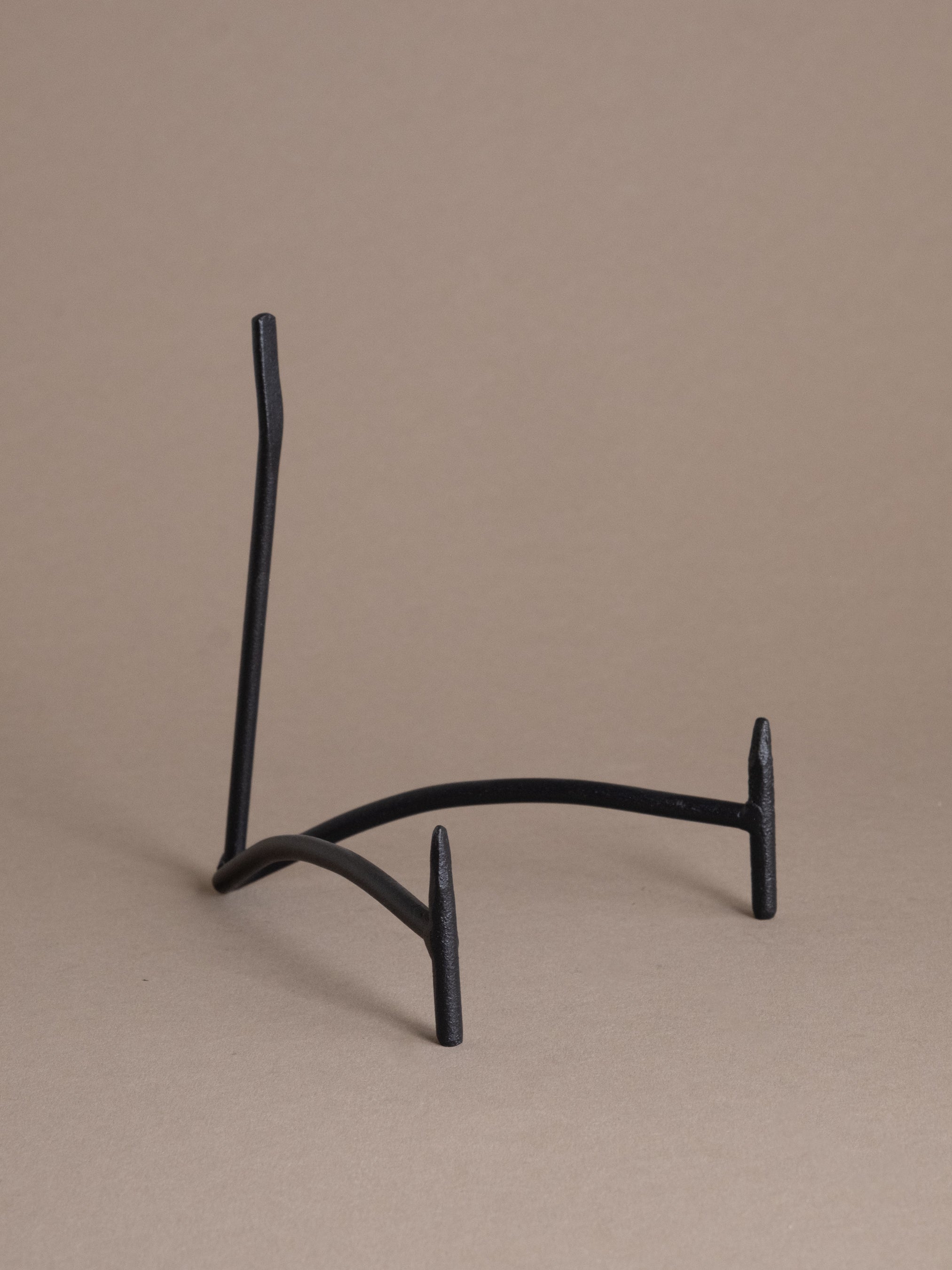 Black iron plate display stand shown empty against a taupe background, designed for displaying plates, shallow bowls, and small objects