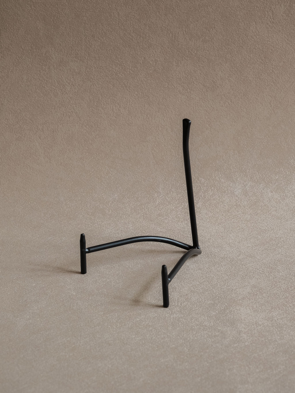 Large black iron plate stand viewed from the reverse side, showing the curved base and angled back support
