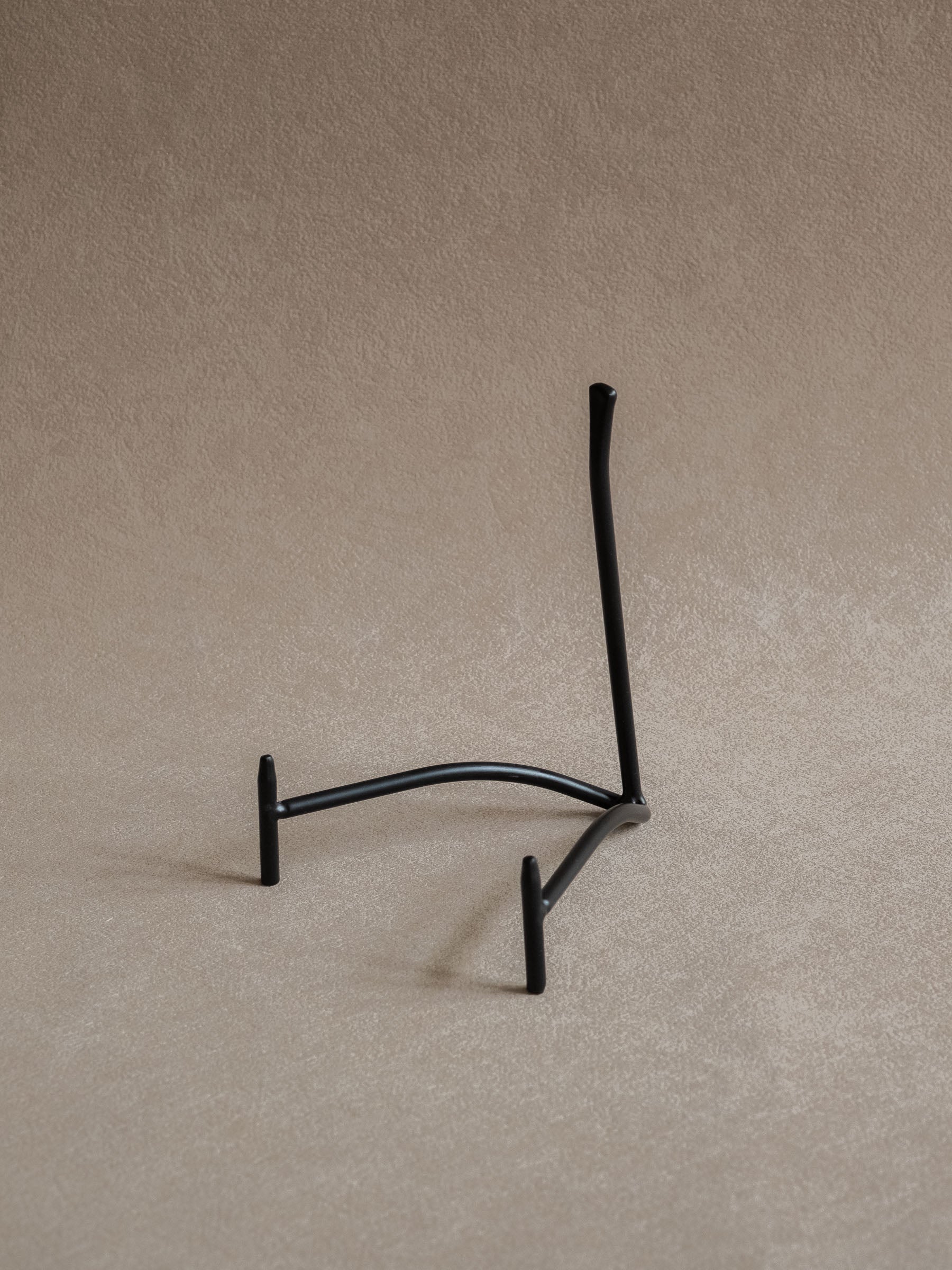 Large black iron plate stand viewed from the reverse side, showing the curved base and angled back support
