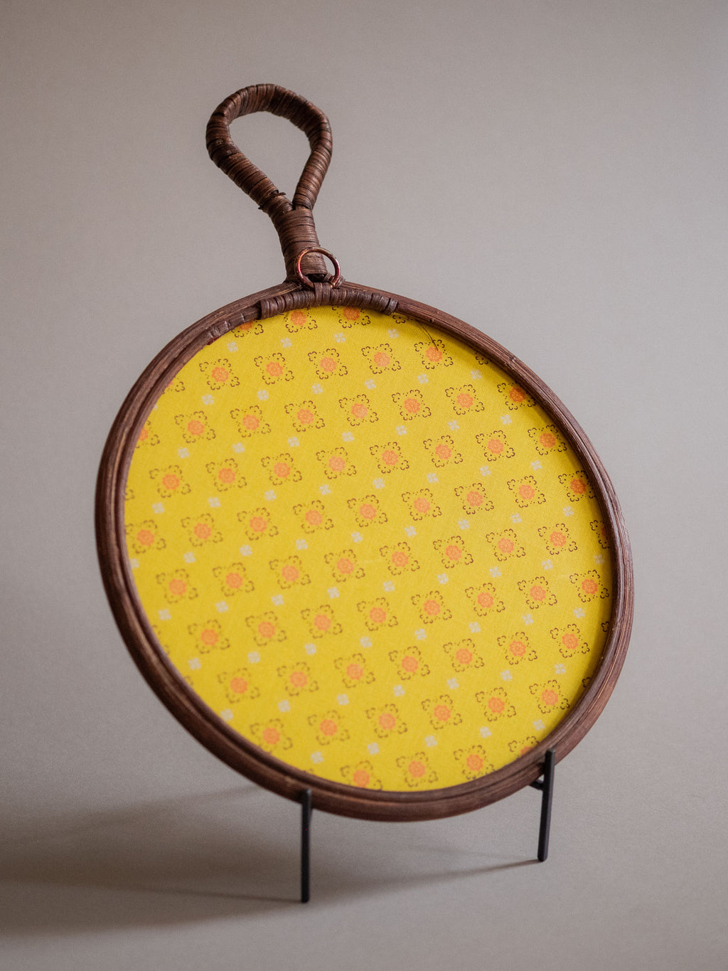 Back view of the round rattan wall mirror showing the shallow depth, beaded border, and loop handle.