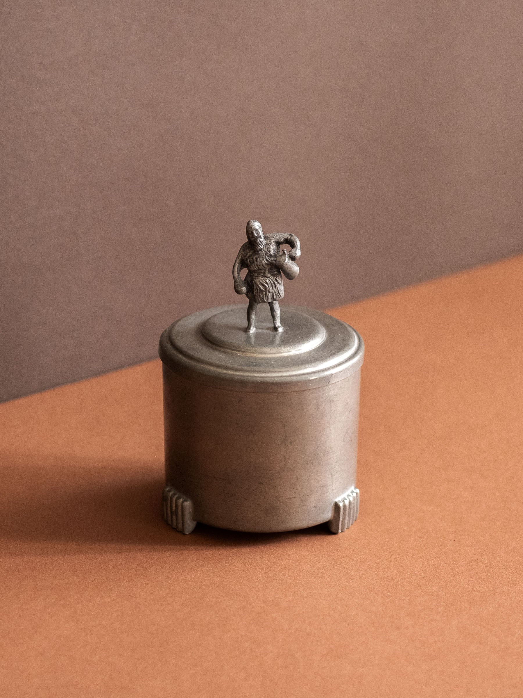 Angled view of the figural finial on the lid of a small Savo Tinn pewter lidded box from Norway.
